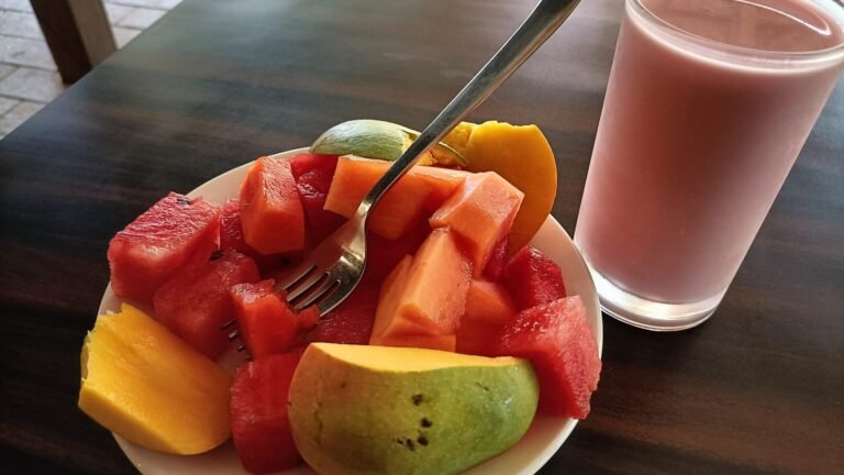 Plato con trozos de sandía, papaya y mango frescos junto a un jugo, frutas que pueden comer los perros
